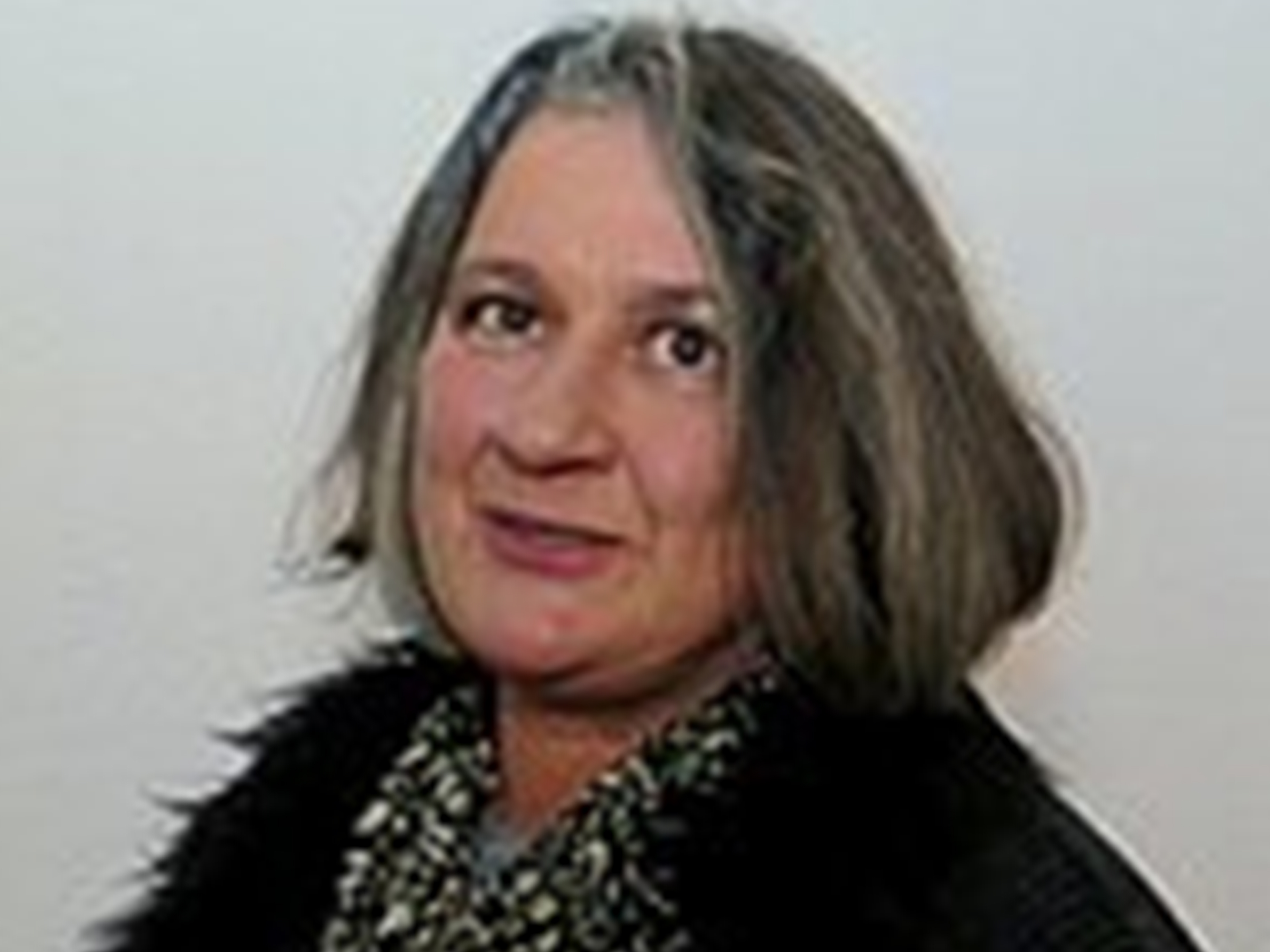 Porträt einer Frau mit grauen Haaren und einem gemusterten Schal.