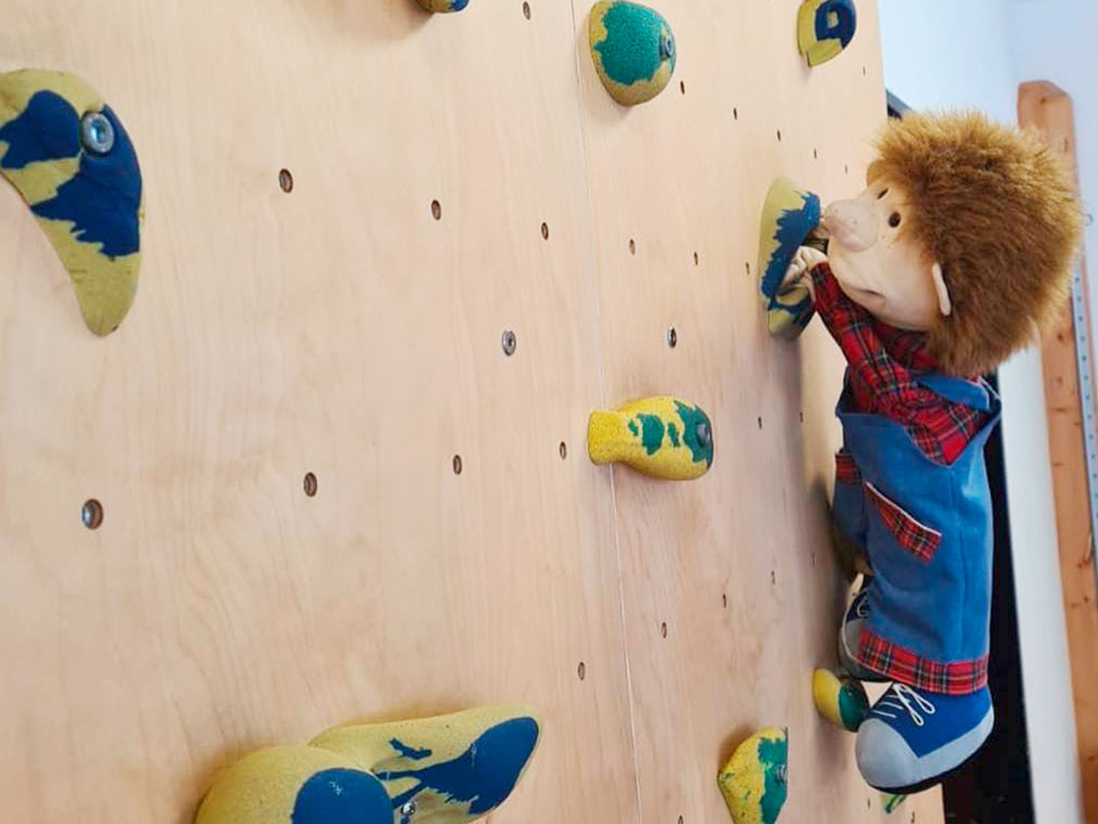 Eine Puppe klettert an einer Kletterwand.