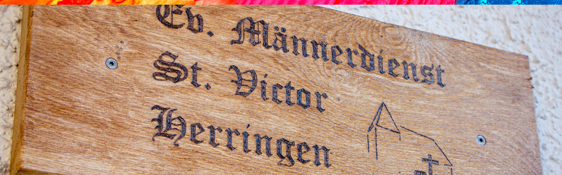 Holzschild: „Ev. Männerdienst St. Victor Herringen“.