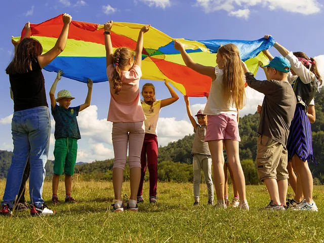 Kinder halten ein buntes Tuch im Freien.
