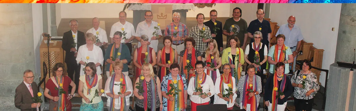 Eine große Gruppe von Menschen, viele mit bunten Schals, posiert für ein Gruppenfoto.
