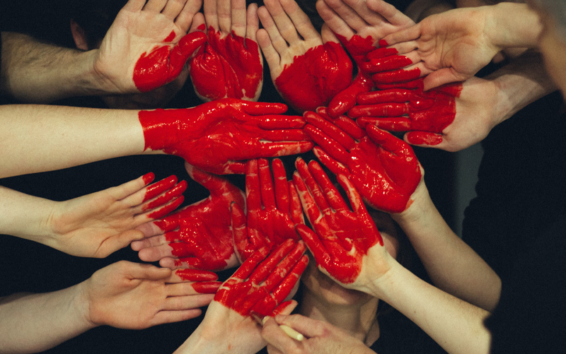 Viele Hände bilden ein rotes Herz.